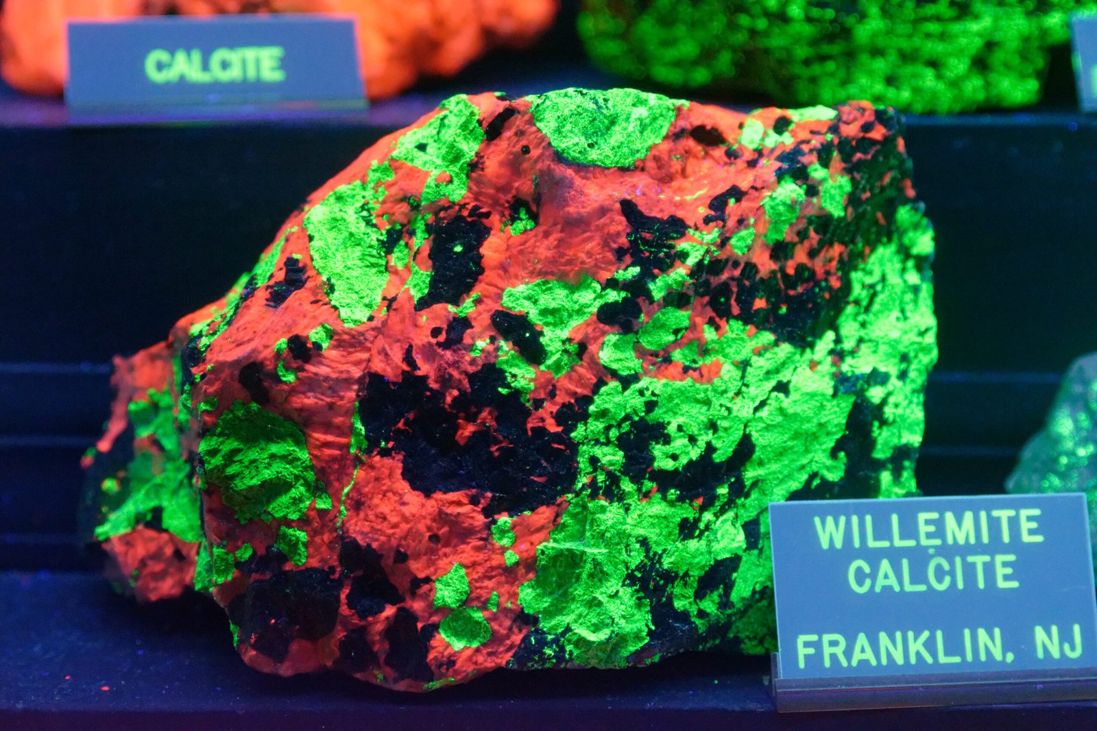 Willemite fluorescant en vert vif et calcite en rouge sous lumière ultraviolette